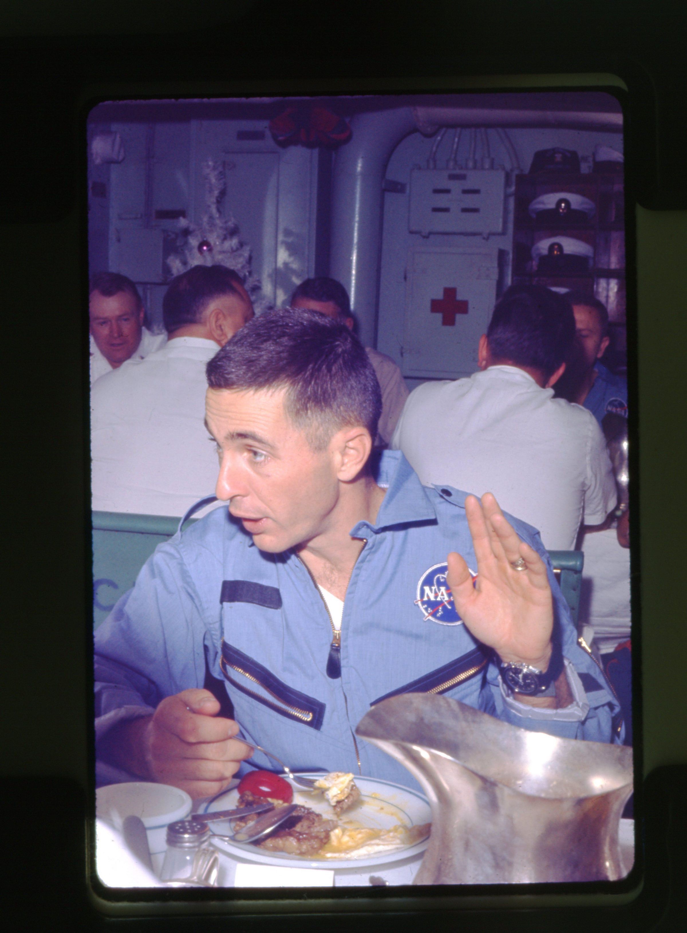 Primary Image of Astronaut William Anders Enjoys a Meal Aboard The USS Yorktown (CVS-10)
