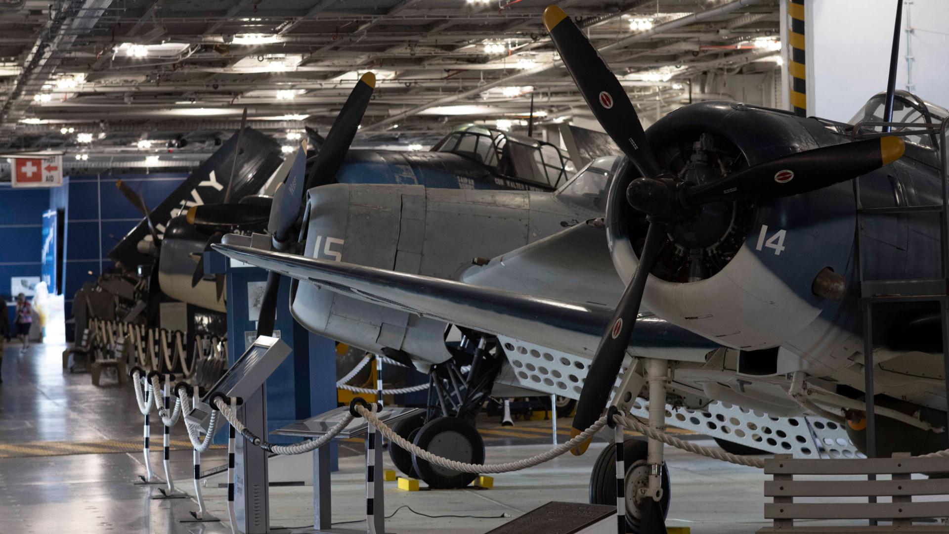 image of a row of aircraft inside the hanger deck of an aircraft carrier