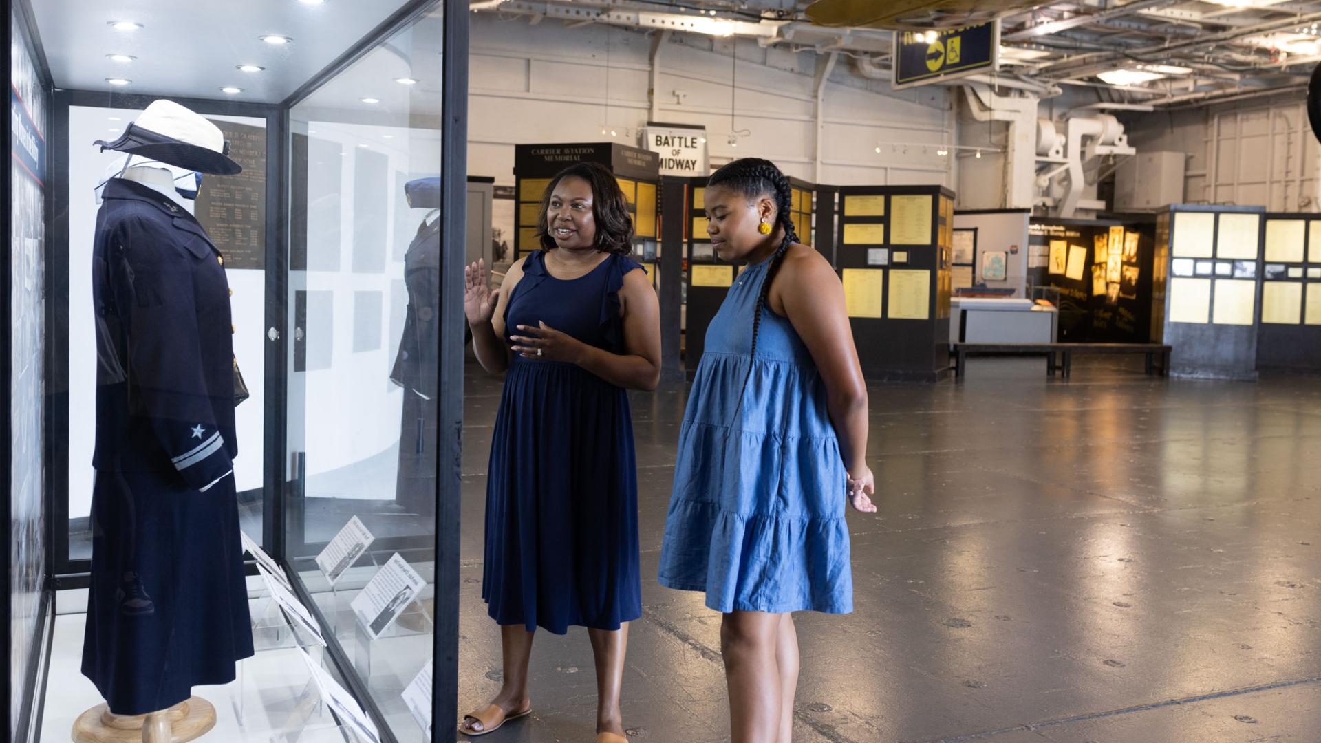 a mother and daughter look at a display behind glass in an aviation museum