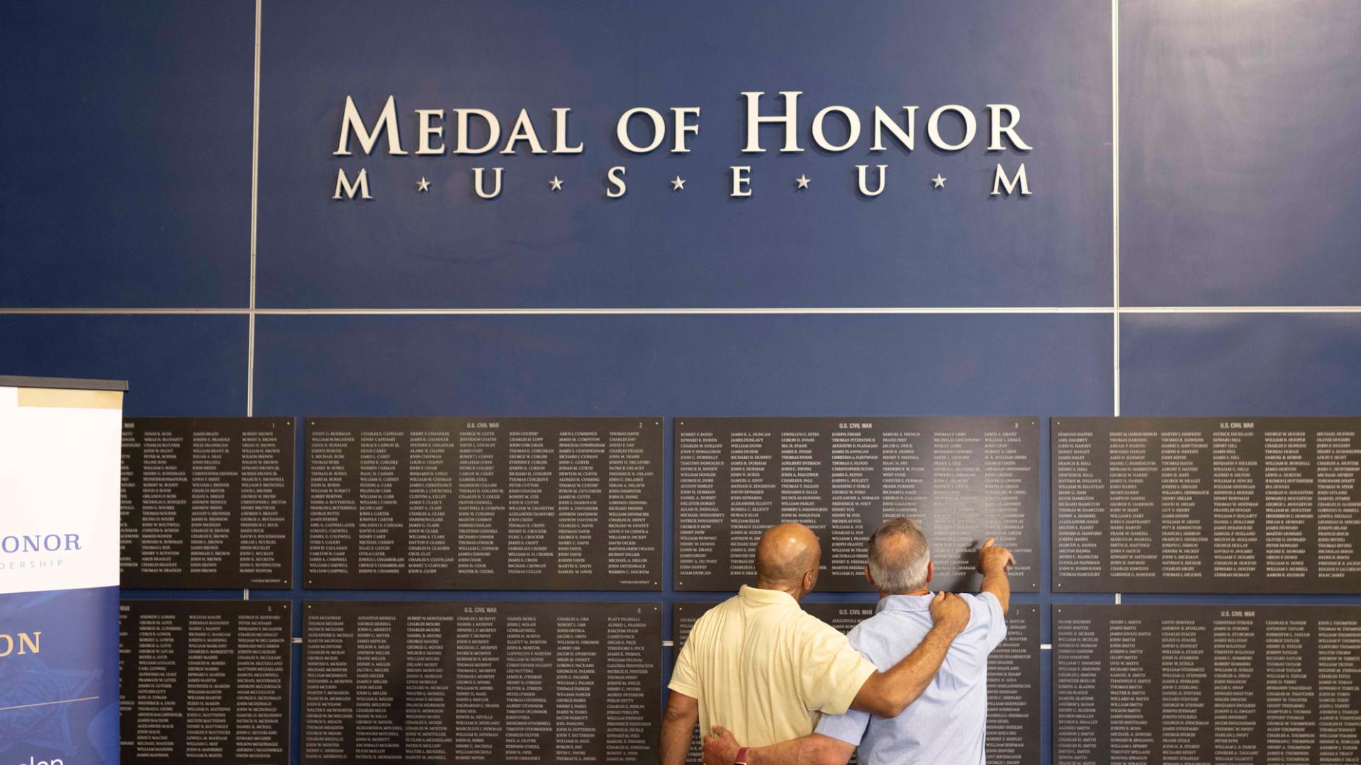 image of two men facing a wall of engraved names under the sign that reads Medal of Honor Museum