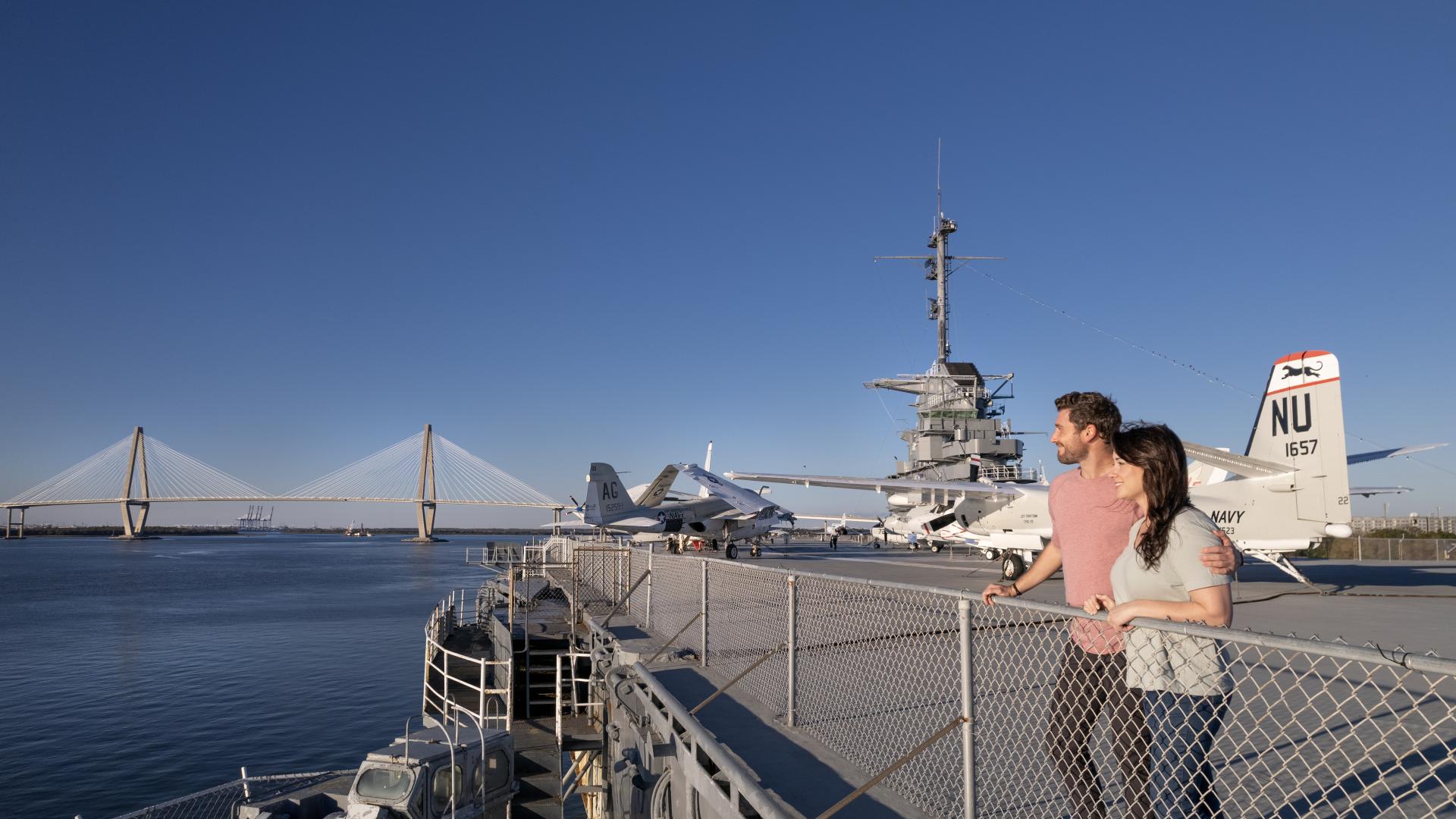 A man and woman stand at the edge of the flight deck overlooking CHS Harbor