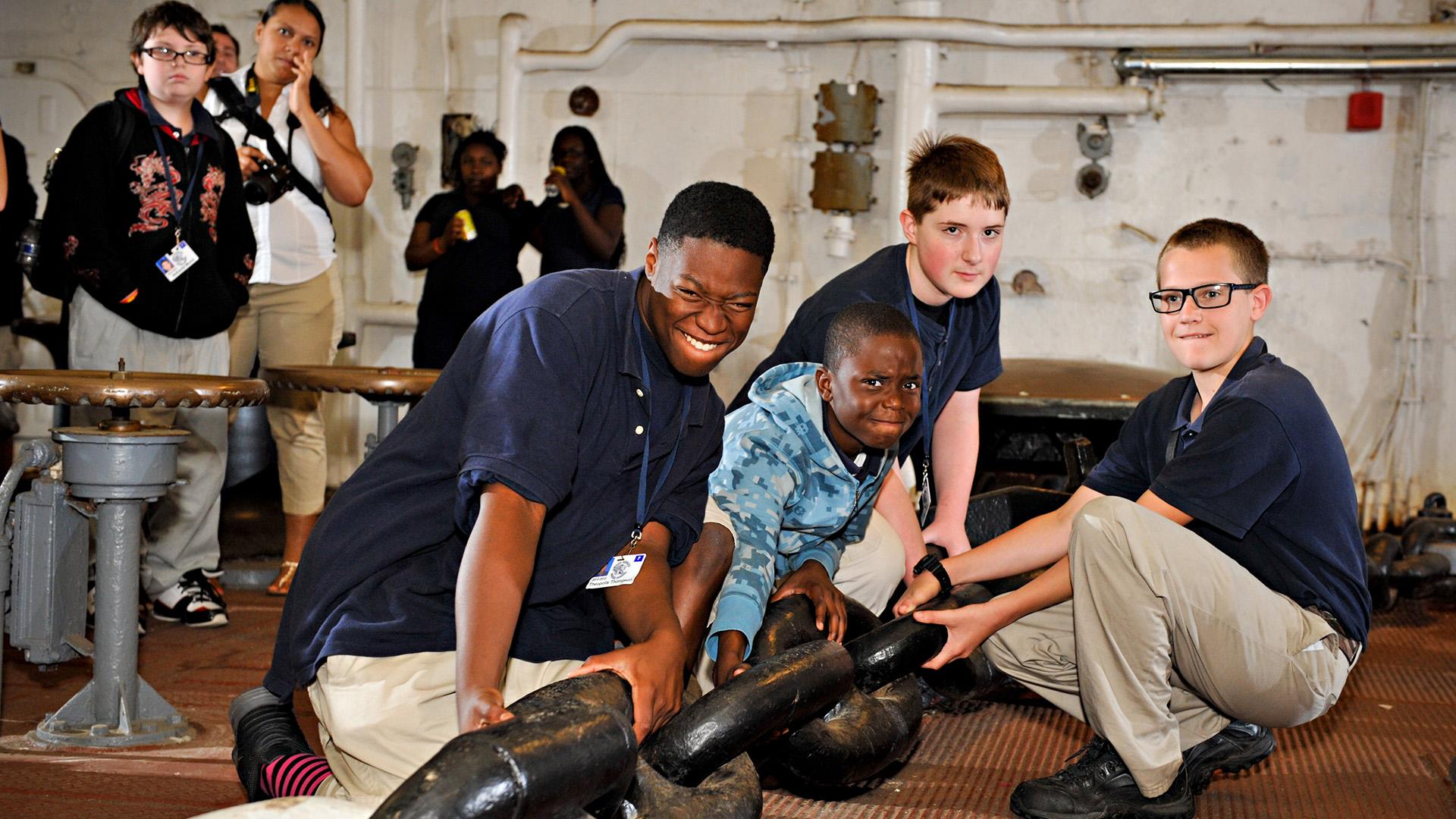 Four boys trying to pull on an anchor chain