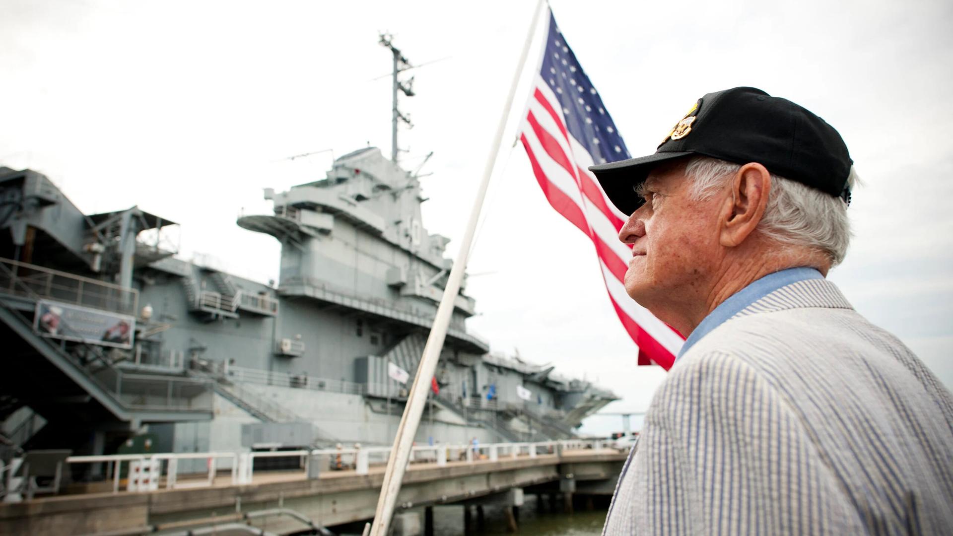 Man standing outside Patriots Point with an American Flag in the background