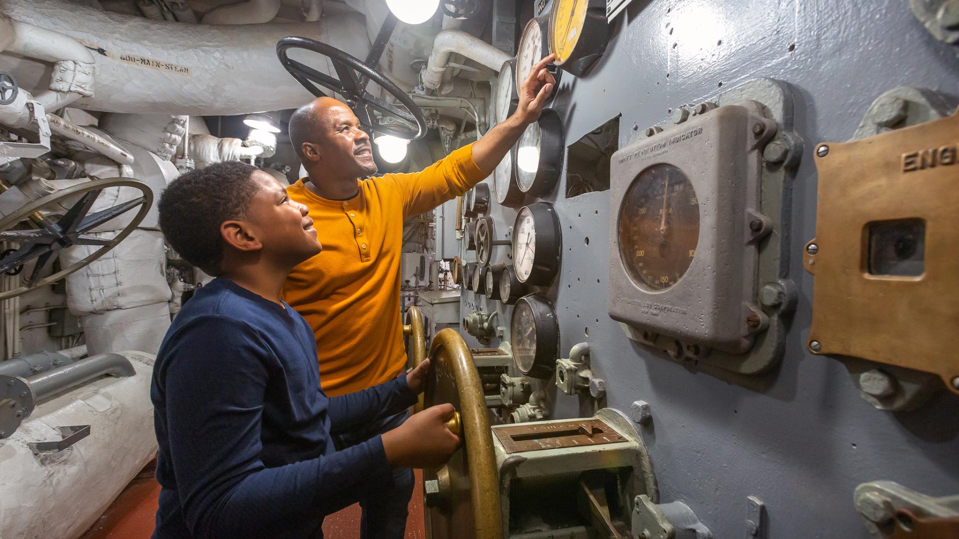 Father and son look at the internal systems on the USS Yorktown.