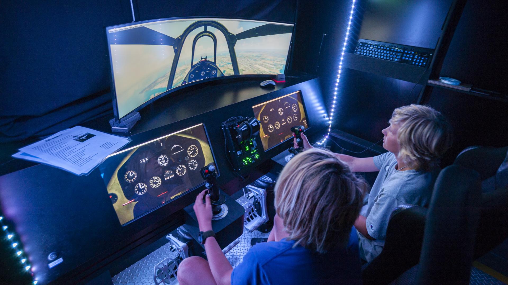 Two kids learning how to pilot a flight simulator.