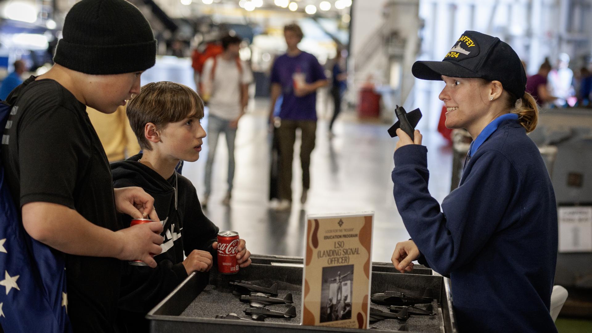 Two kids interact with an education cart while on the hangar deck of the USS Yorktown.