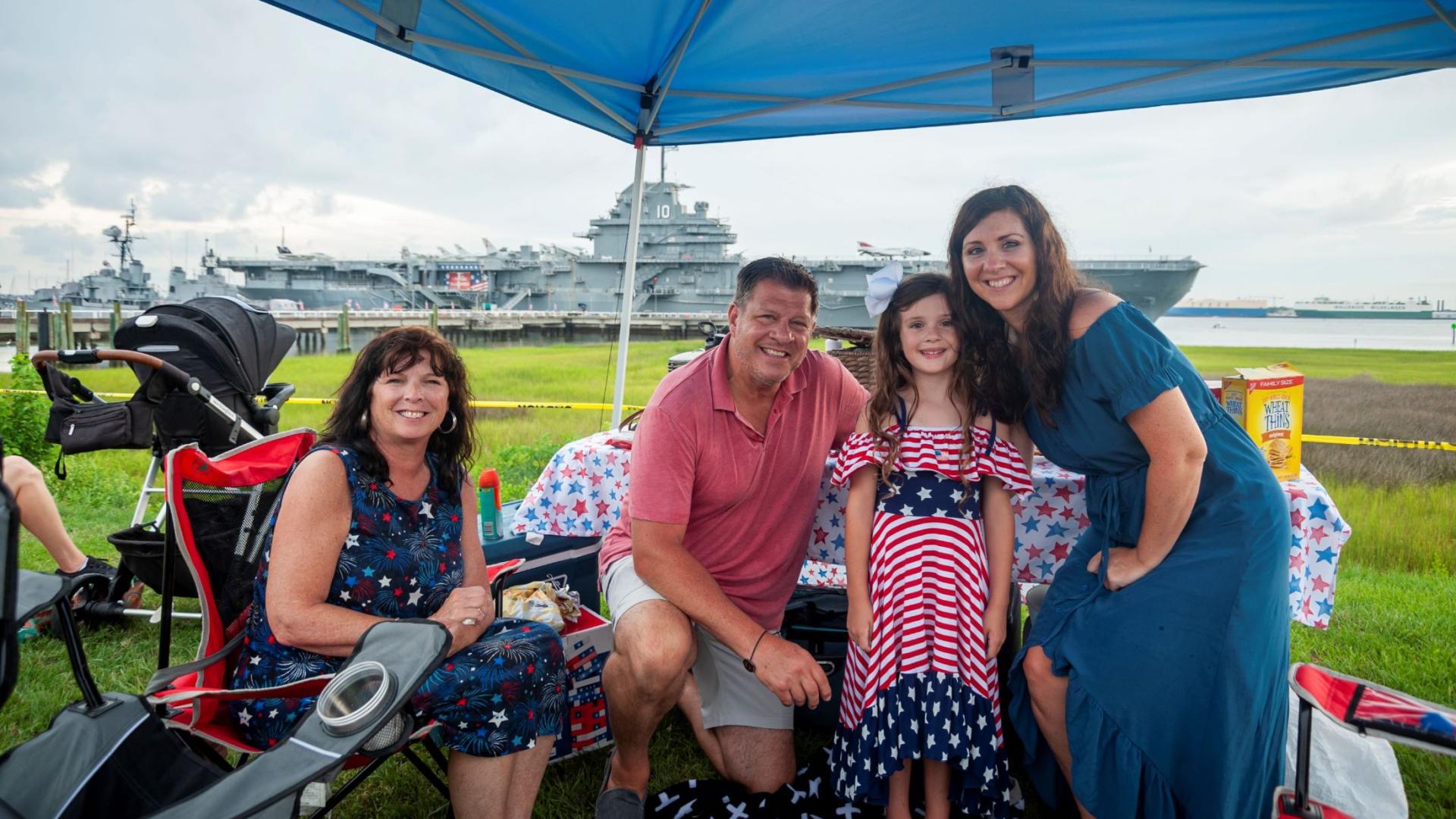 image of a family under a canopy dressed in 4th of July attire in front of the USS Yorktown