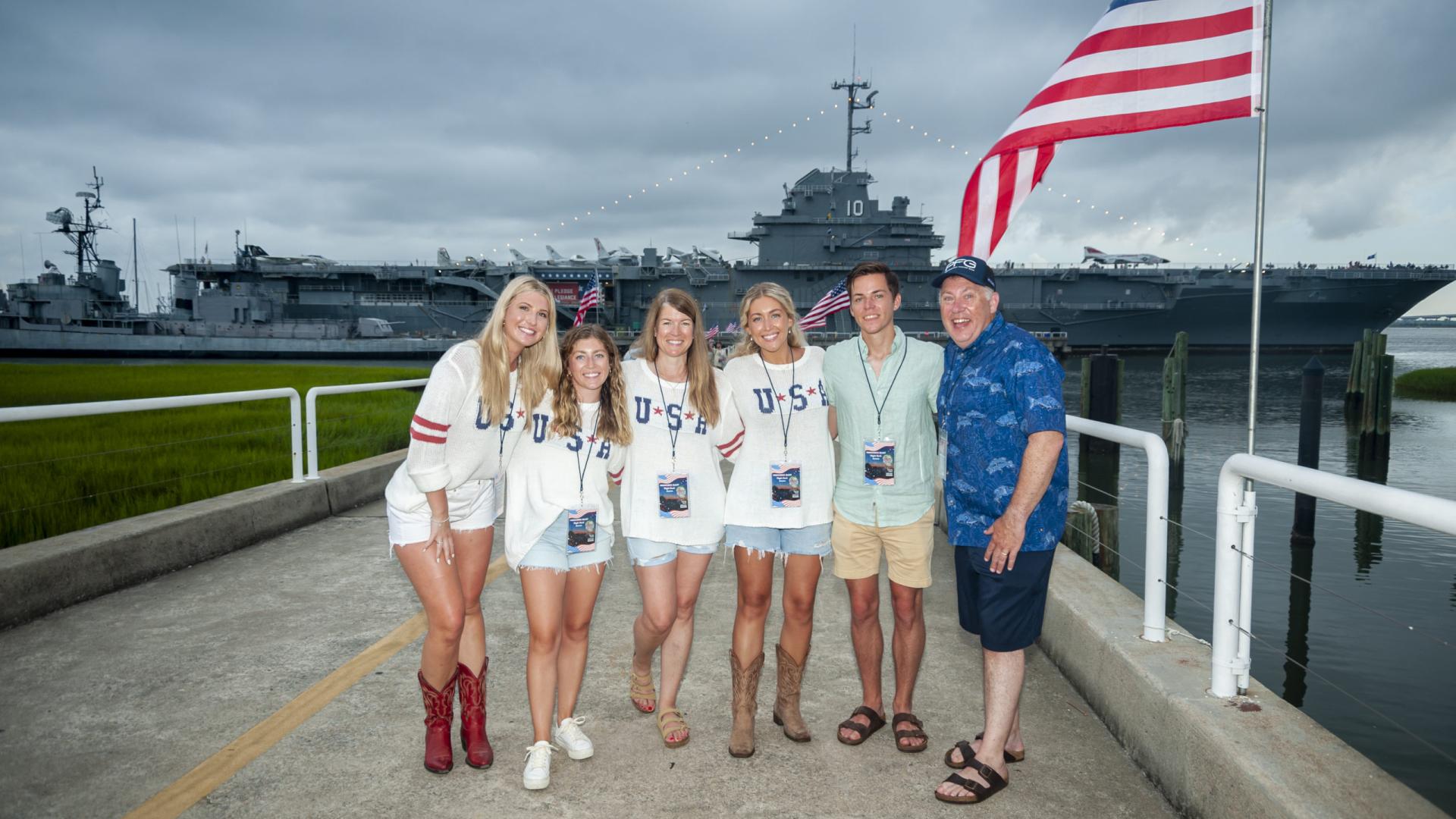 Six individuals in USA shirts stand outside Patriots Point for the Fireworks