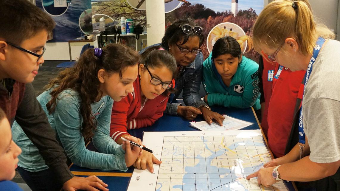 Students stand over a table with a map