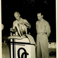 Primary Image of Captain Arnold McKechnie Looking through a Scrapbook at His Farewell Party