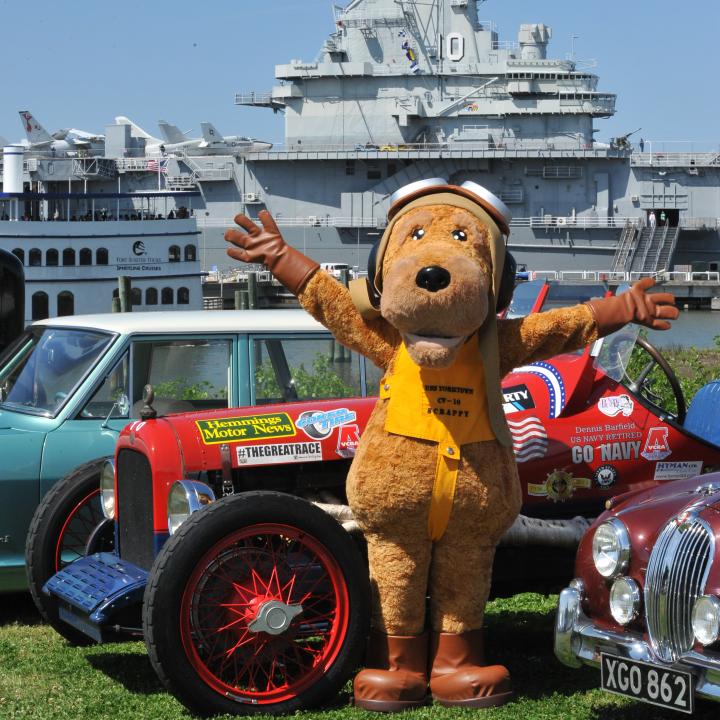 Scrappy, the Patriots Point Naval & Maritime Museum mascot, standing around antique automobiles