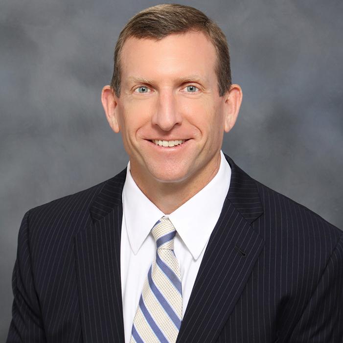 Man with short brown hair in a suit and tie