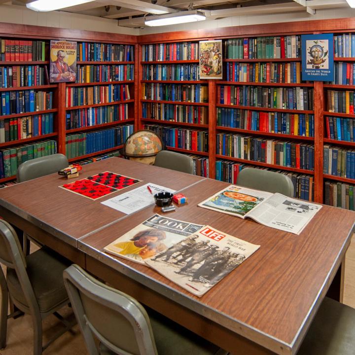 A table sits in the middle surrounds by bookcases filled with books