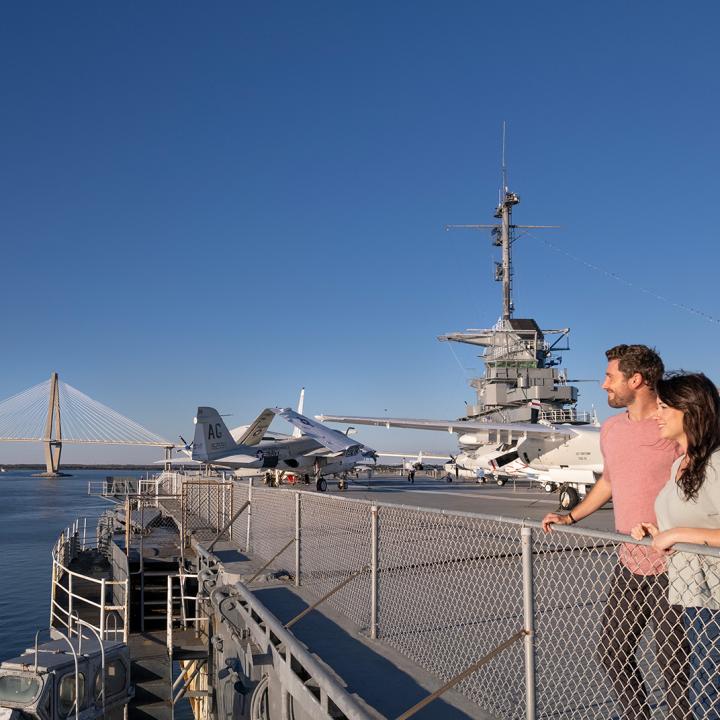 A man and woman stand at the edge of the flight deck overlooking CHS Harbor