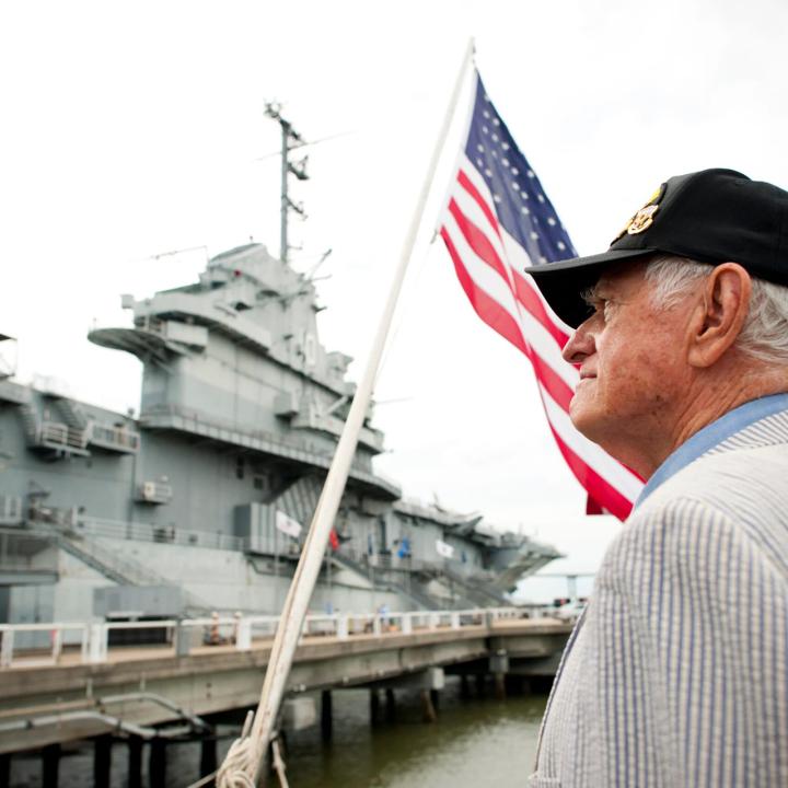 Man standing outside Patriots Point with an American Flag in the background