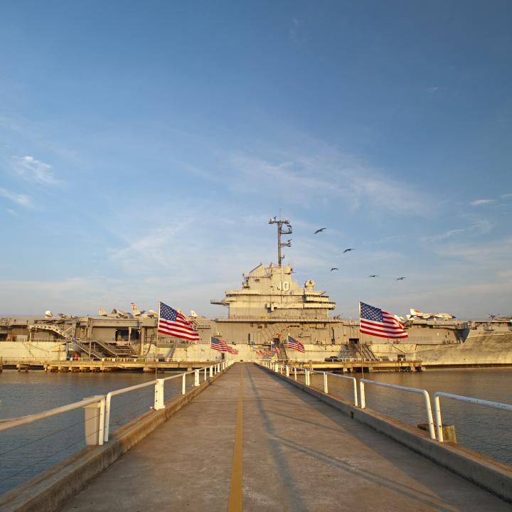Walkway leading to the USS Yorktown aircraft carrier at Patriots Point, adorned with American flags on both sides.