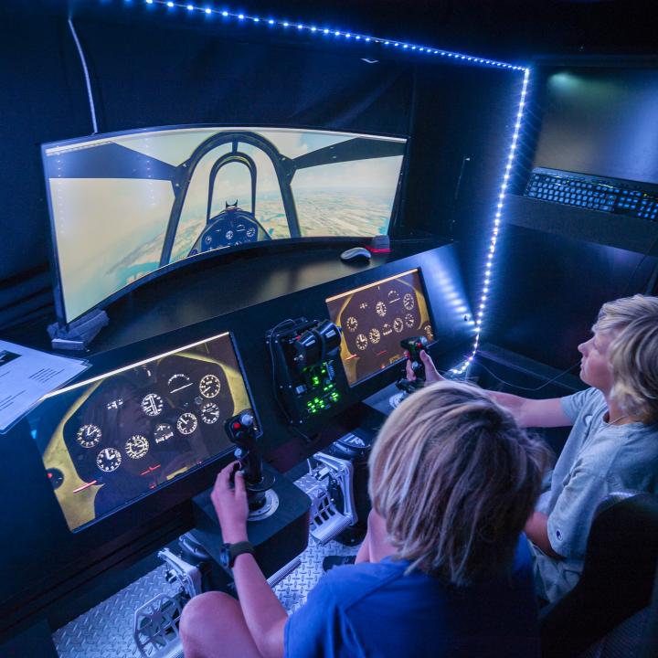 Two kids learning how to pilot a flight simulator.