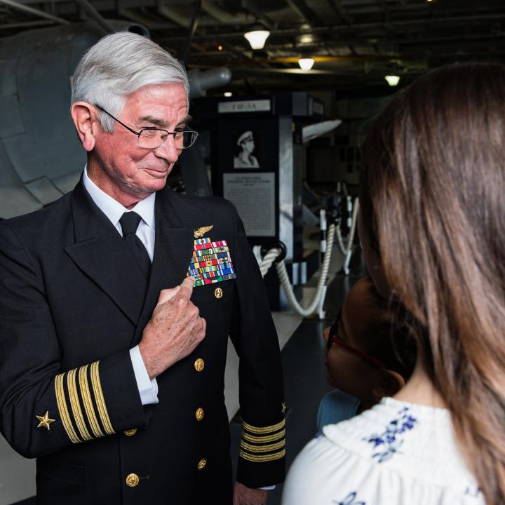 Guests interact with veteran in the hangar bay of the USS Yorktown