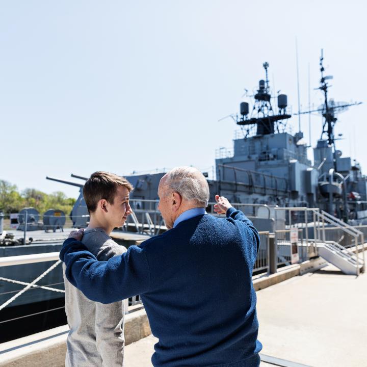 A man and grandson stand near the USS Laffey