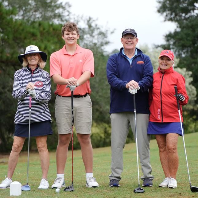 Four people pose for a picture on the golf course.