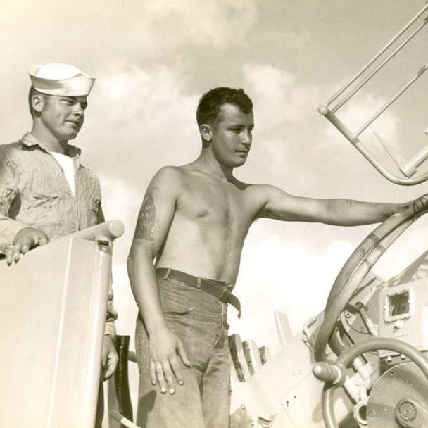 Two men standing outside near one of the 40 mm anti-aircraft guns.