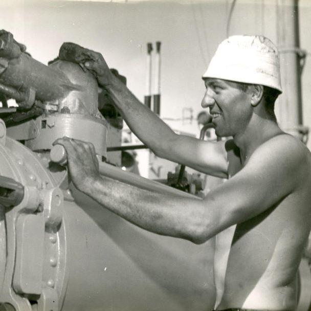 Sailor manning a torpedo launcher on deck.