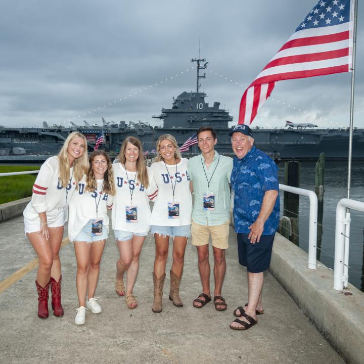 Six individuals in USA shirts stand outside Patriots Point for the Fireworks