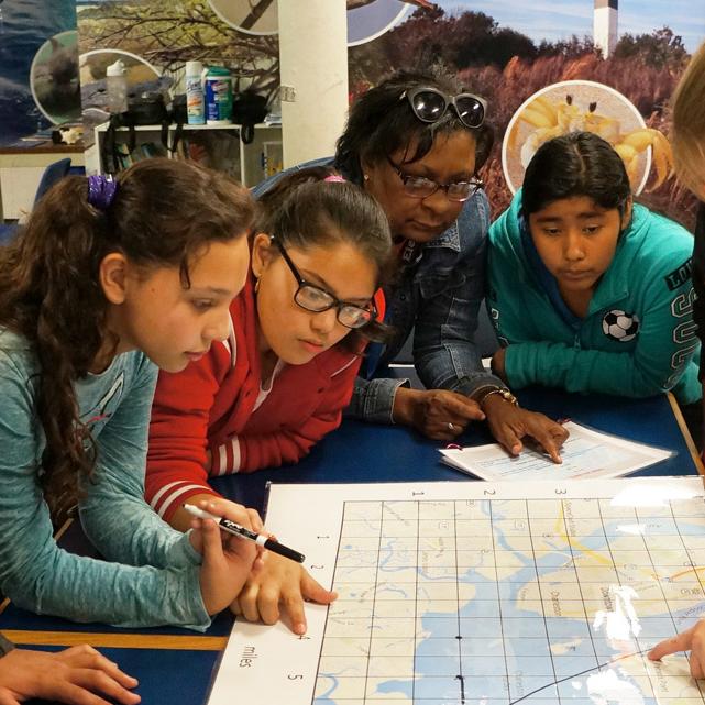 Students stand over a table with a map