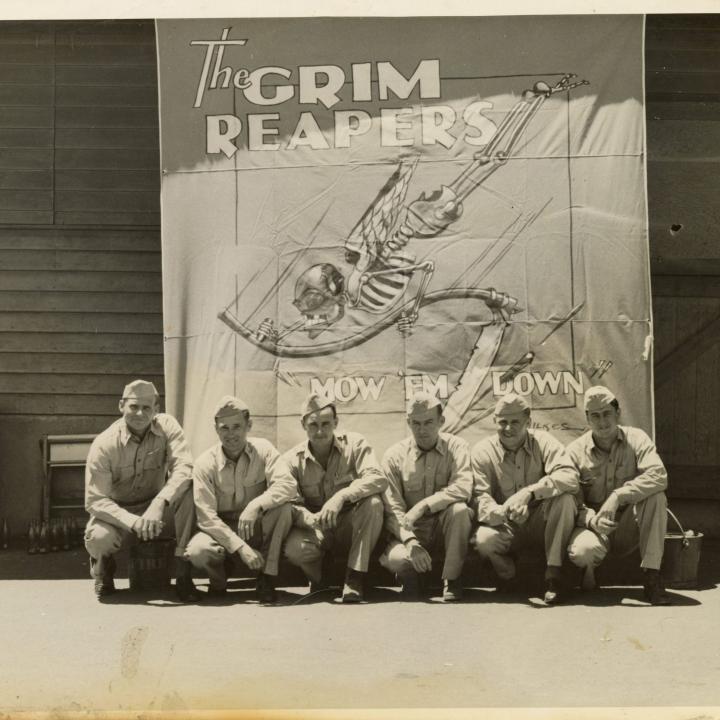 Primary Image of Several Members of Fighting Squadron Ten (VF-10) Sitting in Front of a Grim Reapers Banner