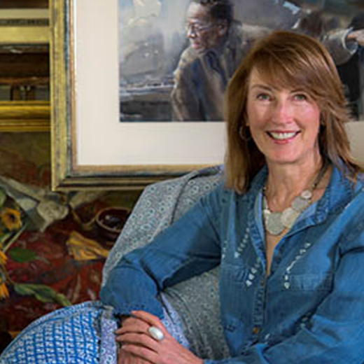 Female with shoulder length brown hair sits in front of some paintings