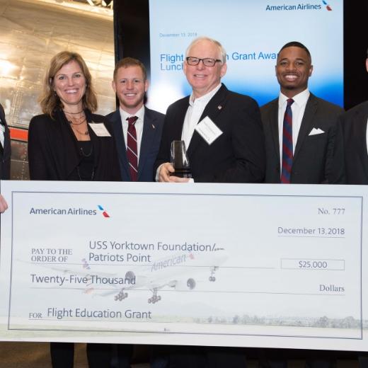 Six individual stand holding a large check made out to the USS Yorktown Foundation for 25,000