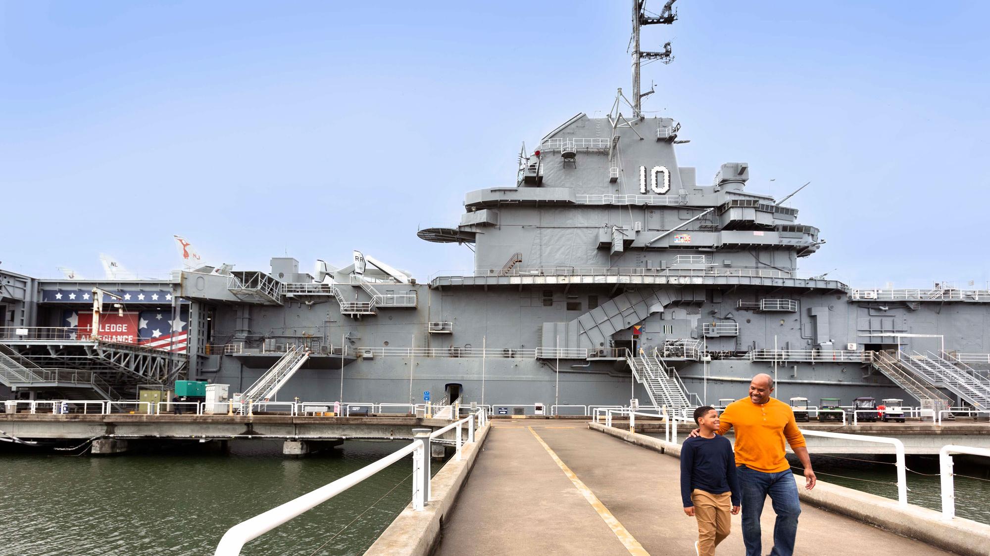image of a father and son walking in front of the USS Yorktown docked in Charleston Harbor