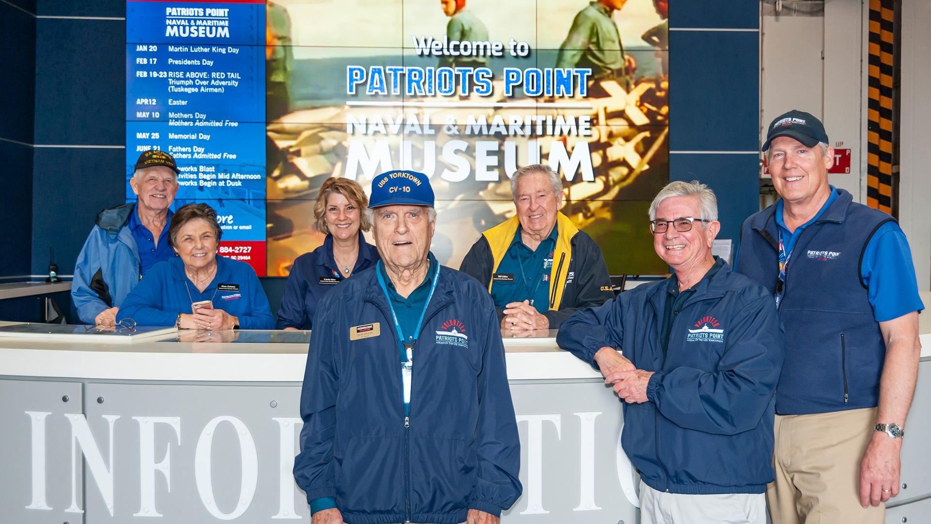 Seven volunteers stand around the information desk