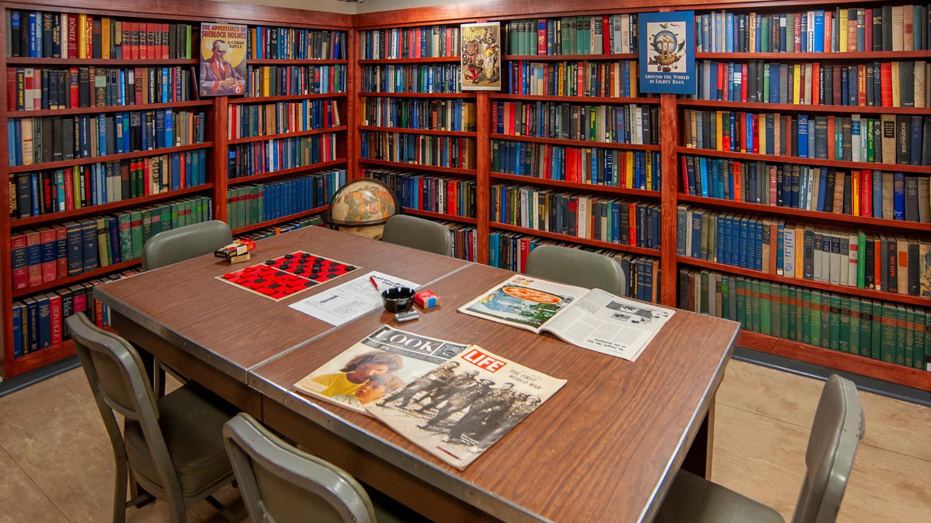 A table sits in the middle surrounds by bookcases filled with books