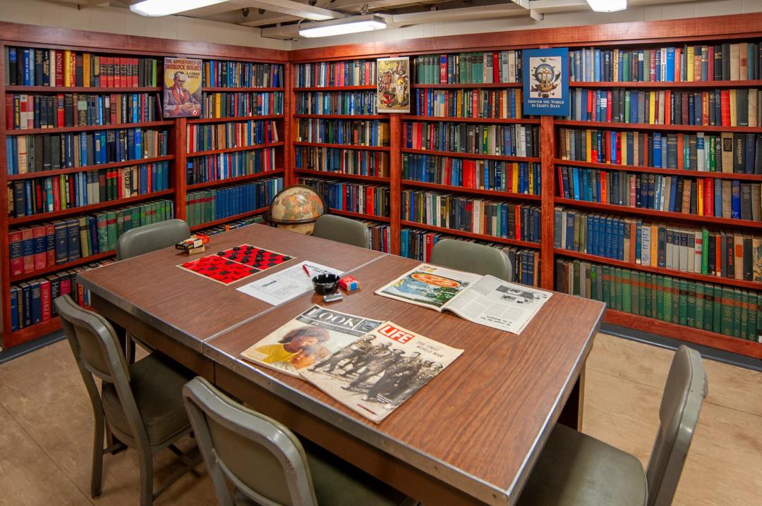 A table sits in the middle surrounds by bookcases filled with books