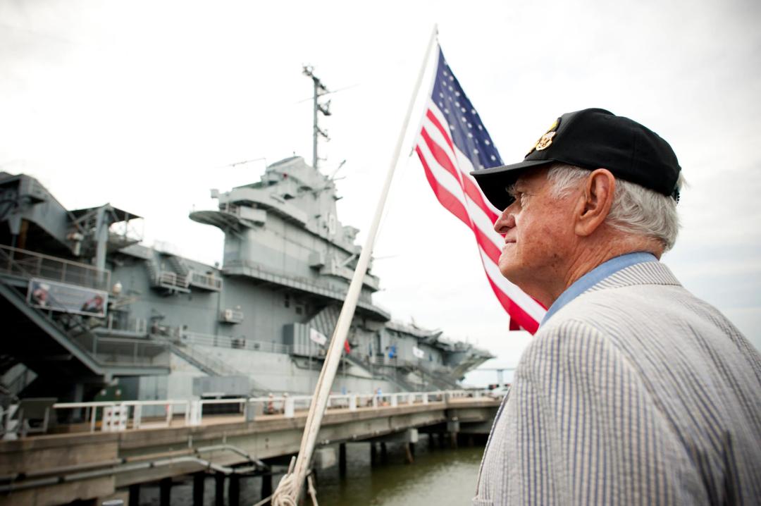 Man standing outside Patriots Point with an American Flag in the background