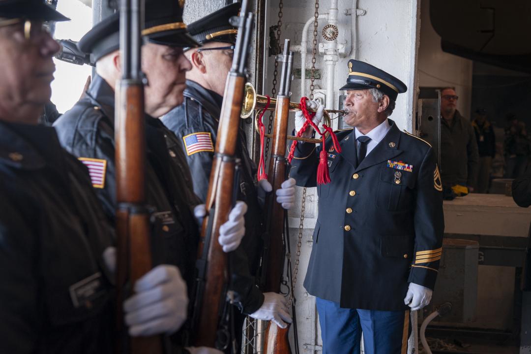 A solemn honor guard ceremony for National Pearl Harbor Remembrance Day aboard the USS Yorktown, with uniformed servicemen standing in formation holding rifles, while a bugler in military dress plays a ceremonial tune.