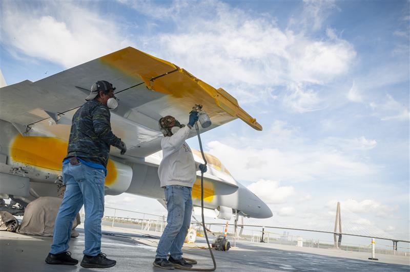 Two men restoring aircraft on the flight deck of the USS Yorktown.