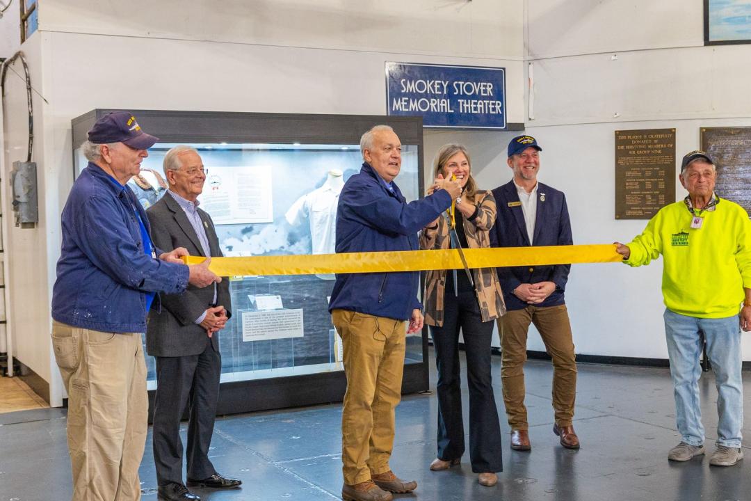 Large ribbon being cut with scissors by distinguished guests.