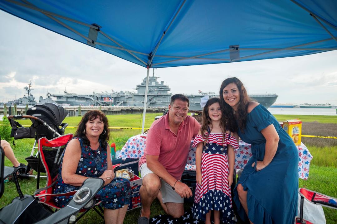 image of a family under a canopy dressed in 4th of July attire in front of the USS Yorktown