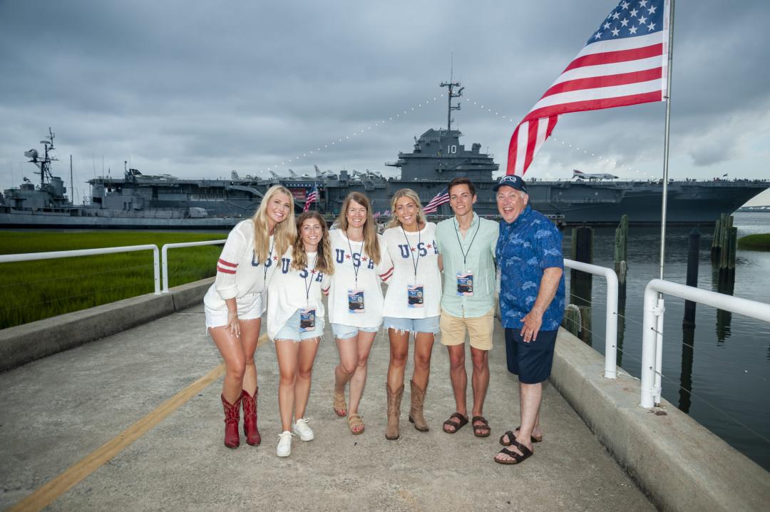 Six individuals in USA shirts stand outside Patriots Point for the Fireworks