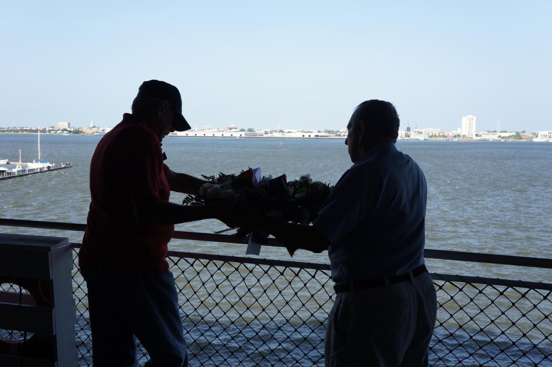 Two men, Tin Can Sailors hang a memorial wreath during the annual reunion