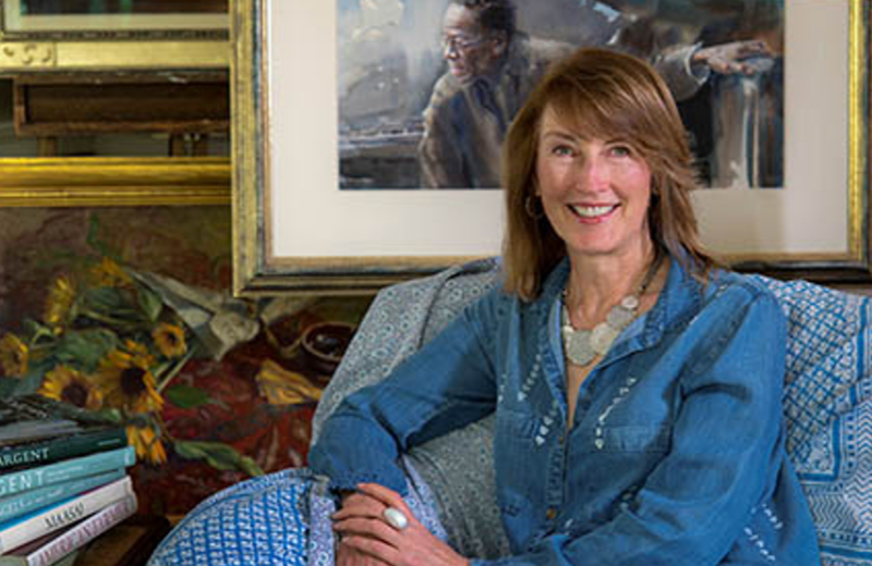 Female with shoulder length brown hair sits in front of some paintings