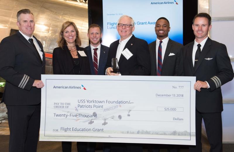 Six individual stand holding a large check made out to the USS Yorktown Foundation for 25,000